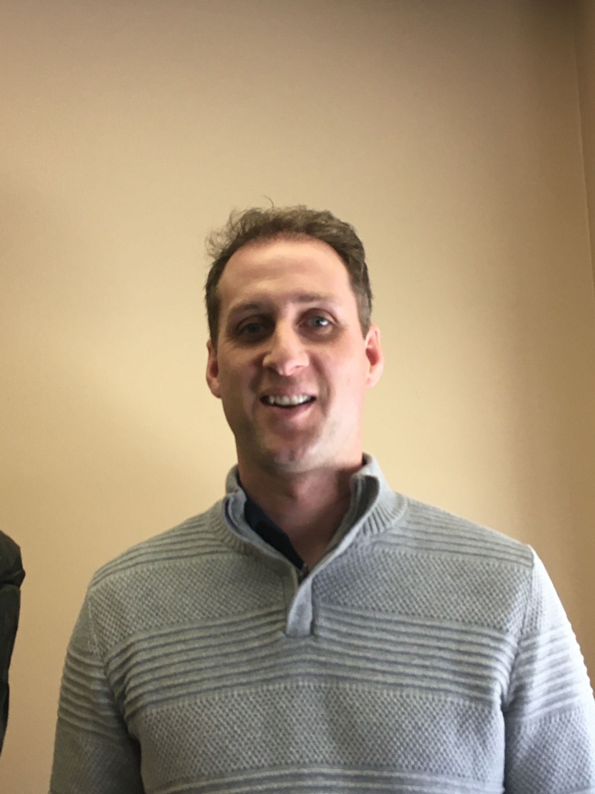 Photo of a man standing in front of a wall.