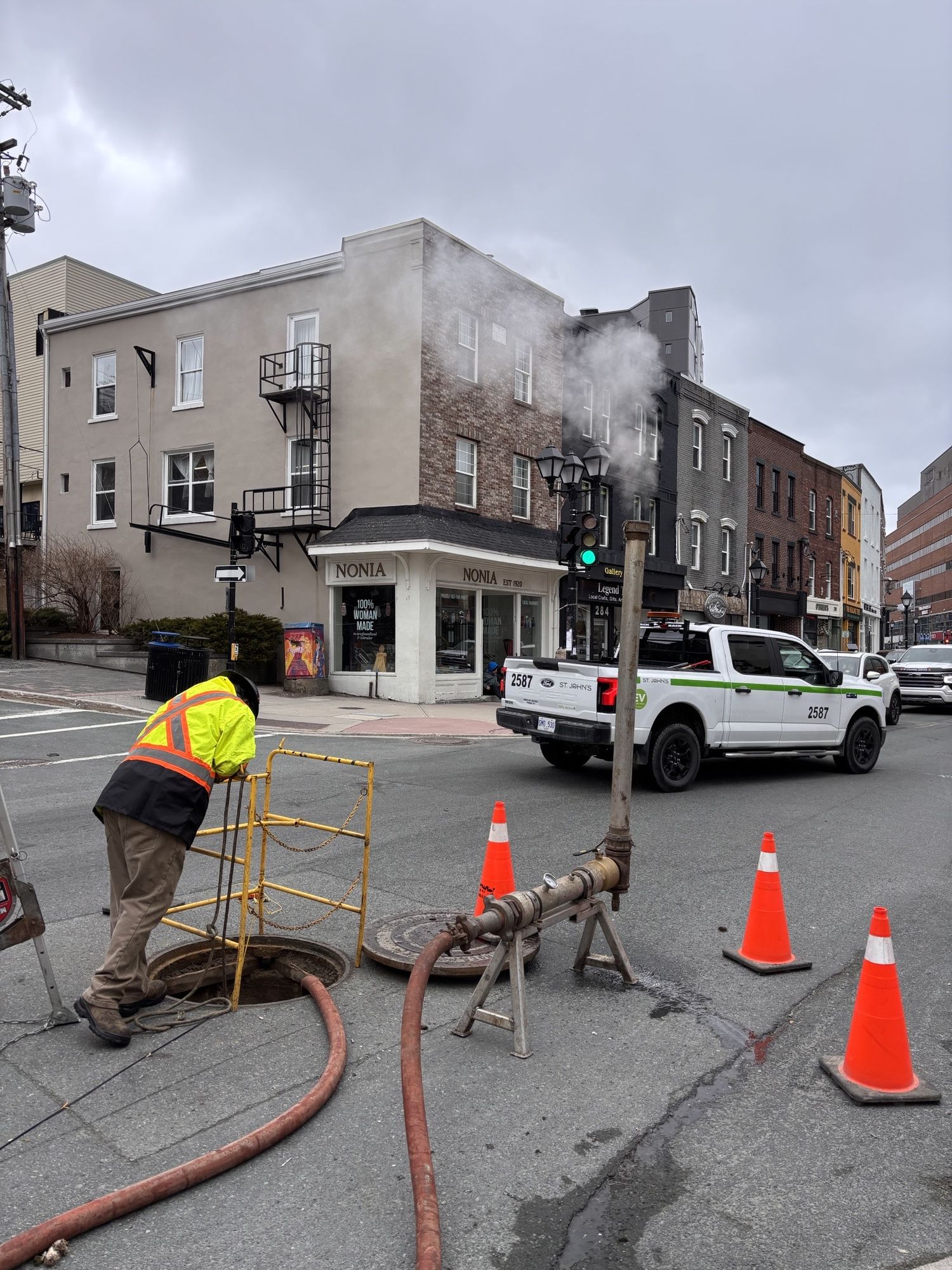 Image of a construction worker looking down a manhole on Water Street