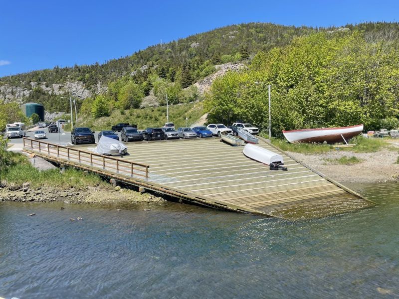 Wooden slip way jutting into the water with boats on it.